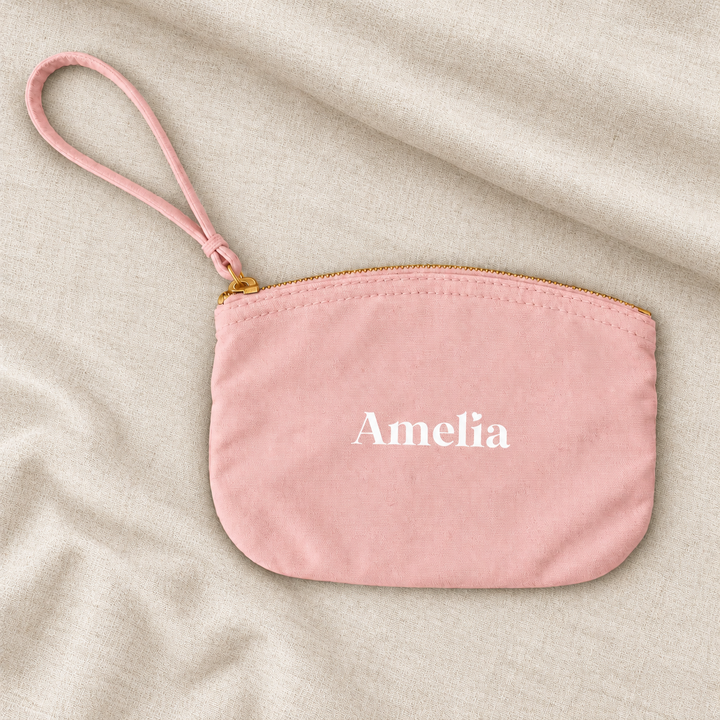 Pink personalised bridesmaid wristlet pouch with the name Amelia, on ivory linen