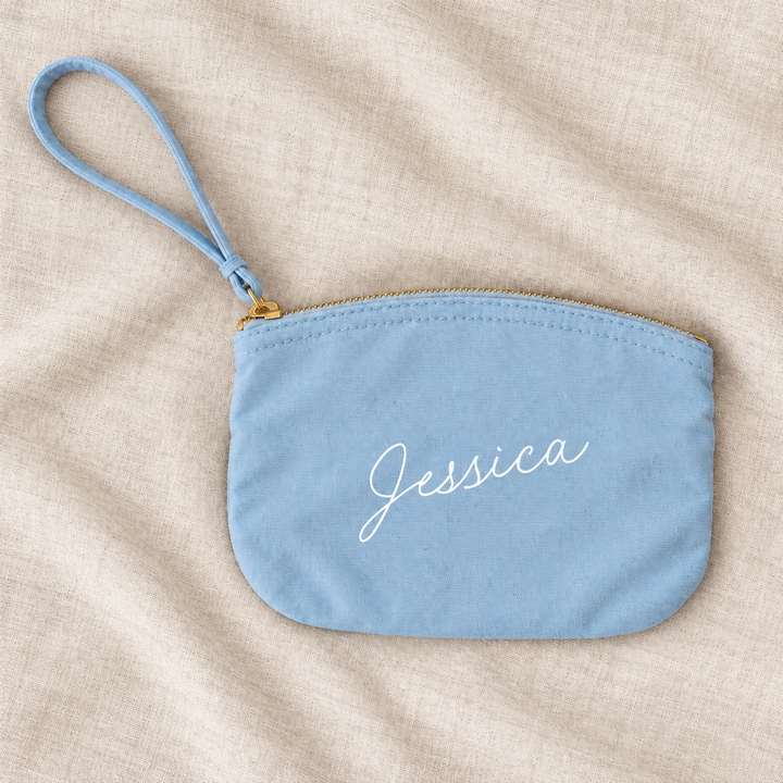 Blue canvas personalised bridesmaid wristlet pouch on ivory linen