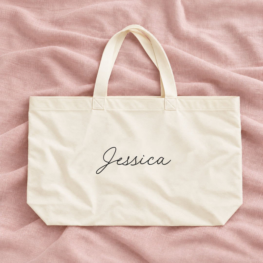 Natural cream canvas personalised bridesmaid XL tote bag with the name Jessica in script, on blush linen