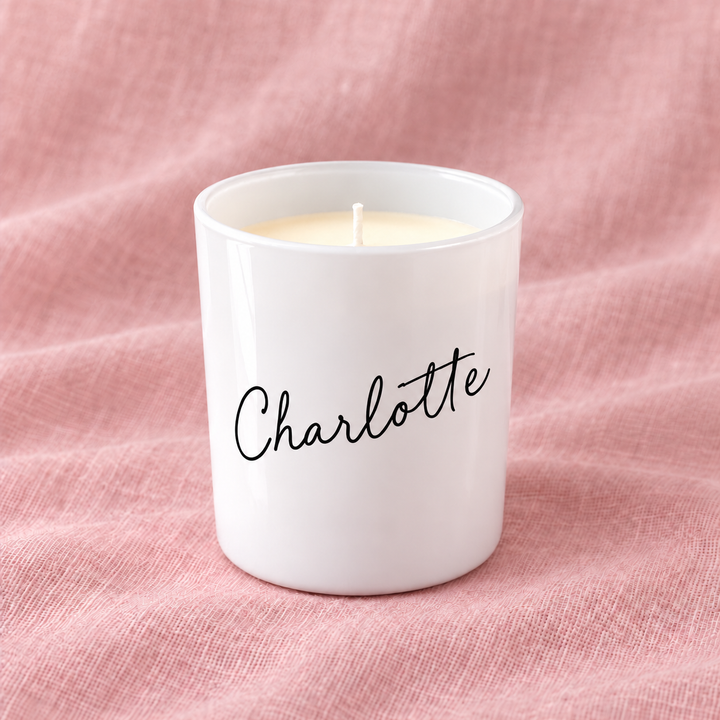 Glossy white personalised bridesmaid candle with the name Charlotte, on pink linen