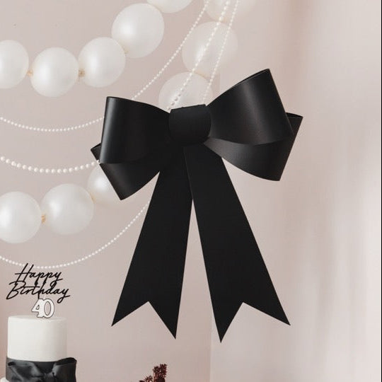 Decorated table for a 40th birthday party with balloons, black bows, and floral arrangements.