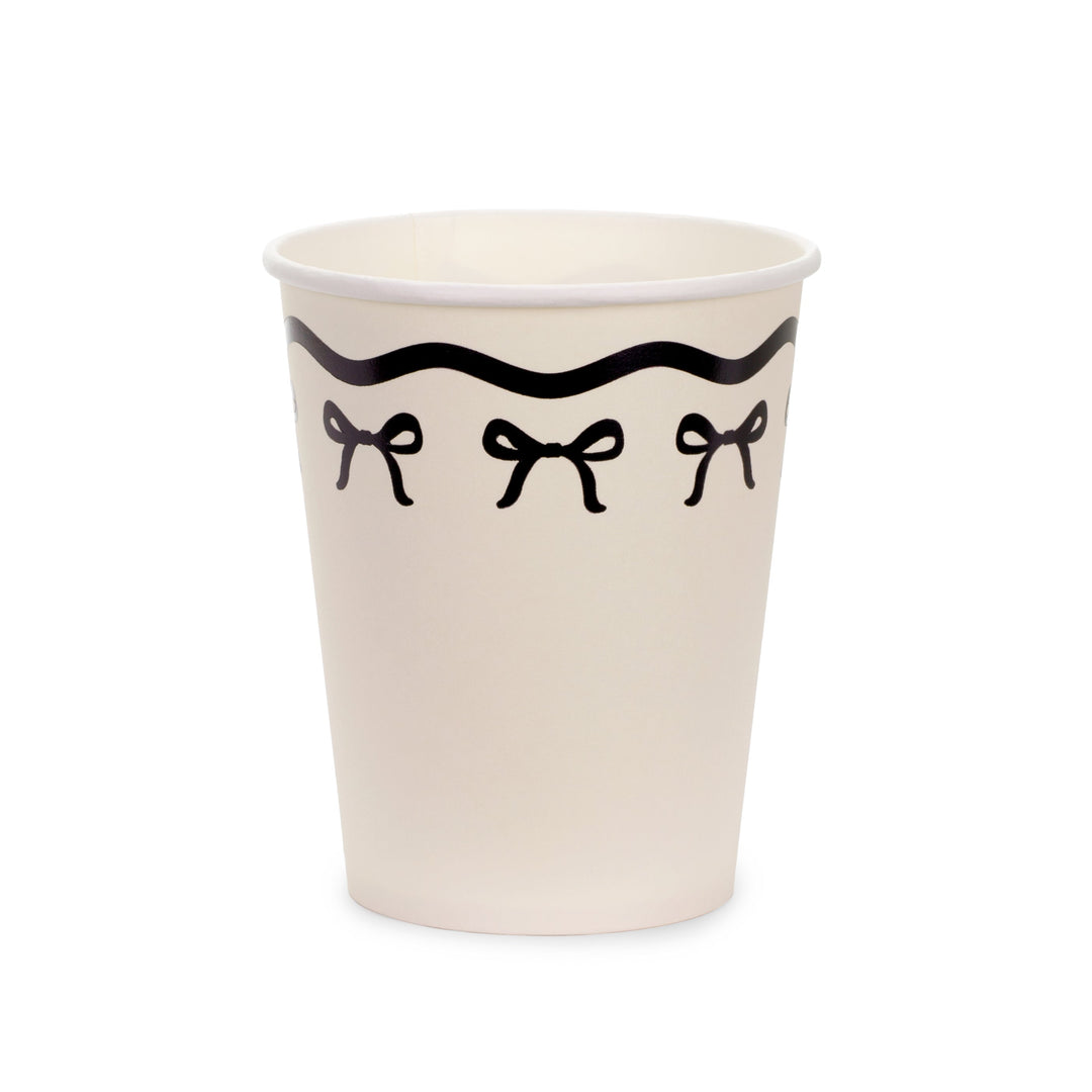 Beige paper cup with black bow design on a white background