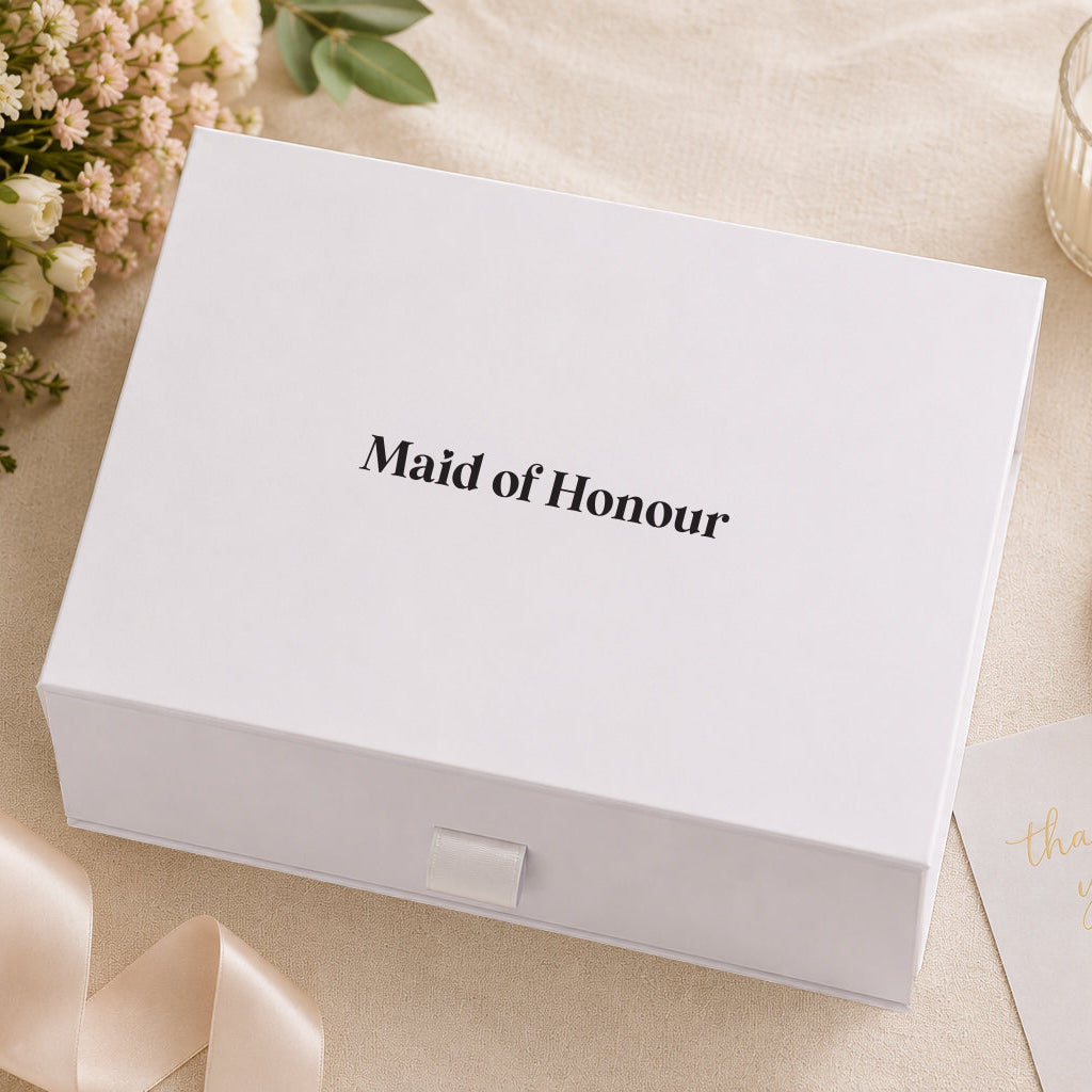 White box labeled 'Maid of Honour' with flowers and a candle on a beige surface